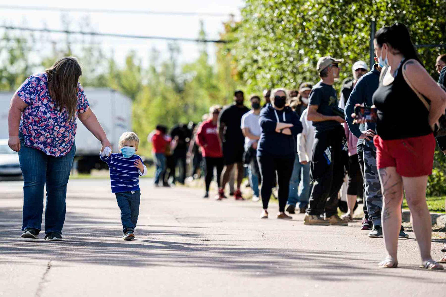 Obese female Hominid cum Balaena abuses human youngling... People wait in line at a mass vaccination and testing clinic at the Moncton Coliseum in Moncton, N.B., on Sept. 22.